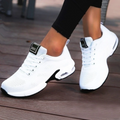A pair of women's black orthopedic running shoes with white accents, designed for comfort and support, displayed on a wooden floor.